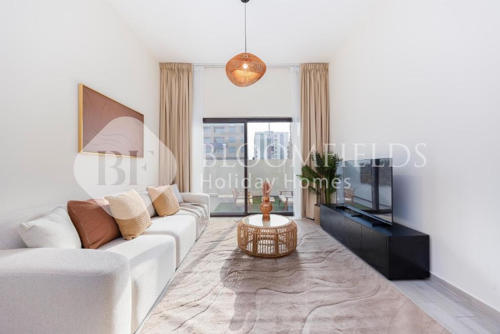 ein Wohnzimmer mit einem weißen Sofa und einem Fernseher in der Unterkunft Bloomfields 2BR Villa Beach Access Fujairah in Fudschaira