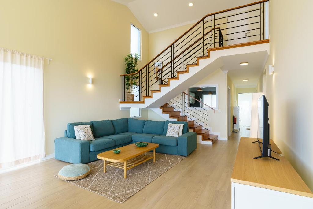 un soggiorno con un divano blu e una scala di Villa Pargo Green by Madeira Dream Stays a Ponta do Pargo