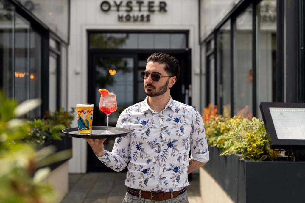 ザ・マンブルズにあるOyster Houseの飲み物とグラスが入ったトレイを持った男性