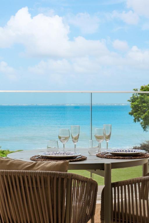 a table with wine glasses on top of the ocean at SEA NOVA Friar's Bay Beachfront Properties in Saint Martin