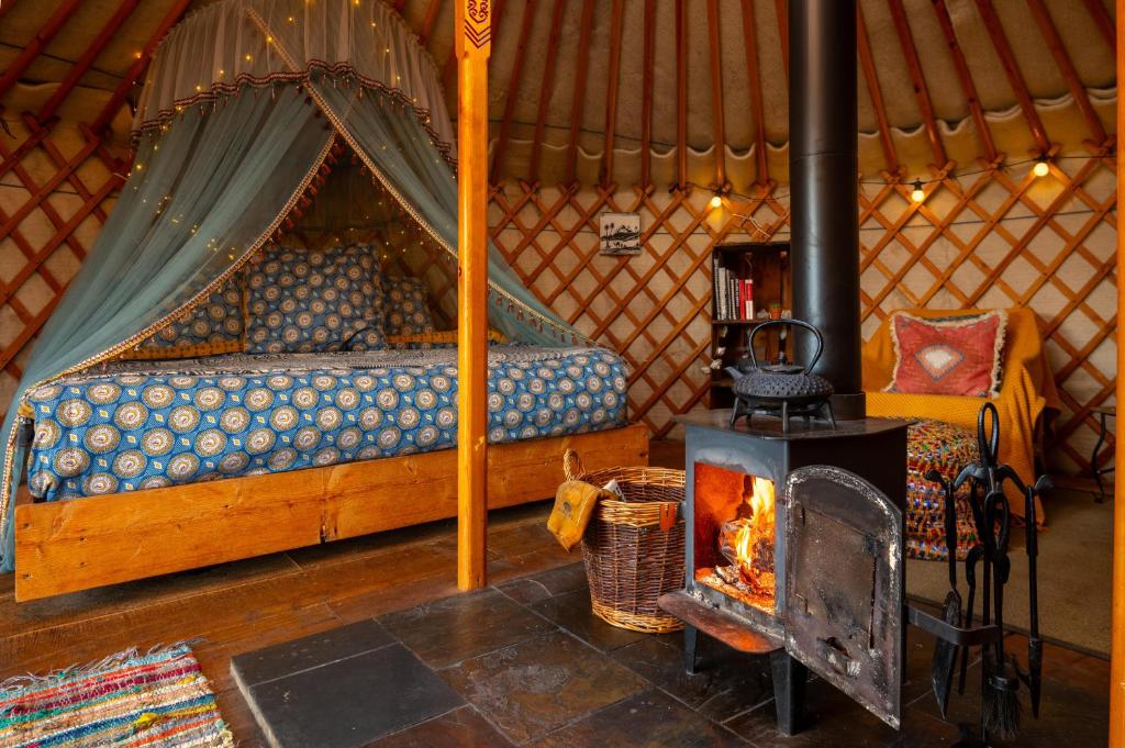 Ein Kamin in einer Jurte mit Bett und Ofen in der Unterkunft Finest Retreats - Pandy Traditional Yurt in Penmaen Pool