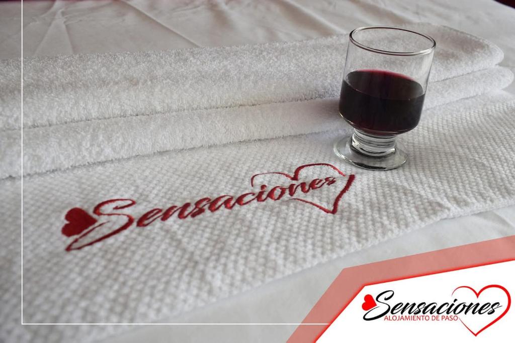 a glass of wine sitting on a bed with towels at Motel Sensaciones in Latacunga