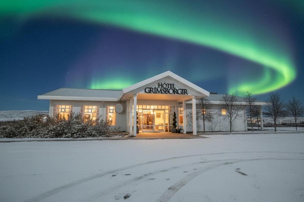 a building with the green northern lights in the sky at Hotel Grimsborgir by Keahotels in Ásborgir