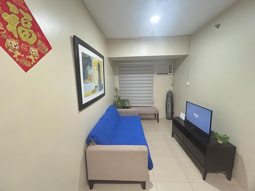 een woonkamer met een blauwe bank en een tv bij 2Bedroom 2Bathroom AvidaRialaTowers with Pool Netflix in Cebu City