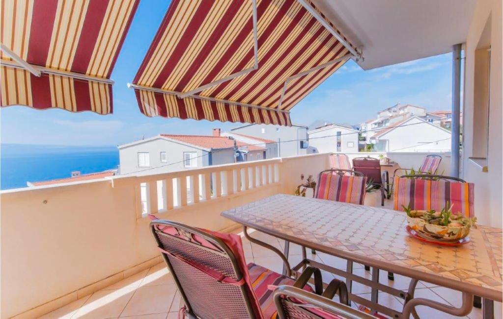 a balcony with a table and chairs and the ocean at Nice Apartment In Omis With Wifi in Tice