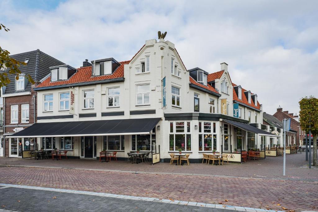 a large white building with tables on a street at Boutique Hotel de Statie in Valkenswaard