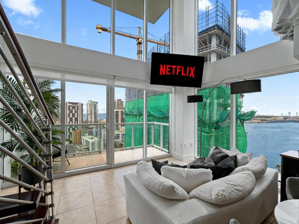 a living room with a white couch in front of a large window at Skyline Serenity - Brickell On The River - Bi-Level Loft with Breathtaking Views On The Ocean in Miami