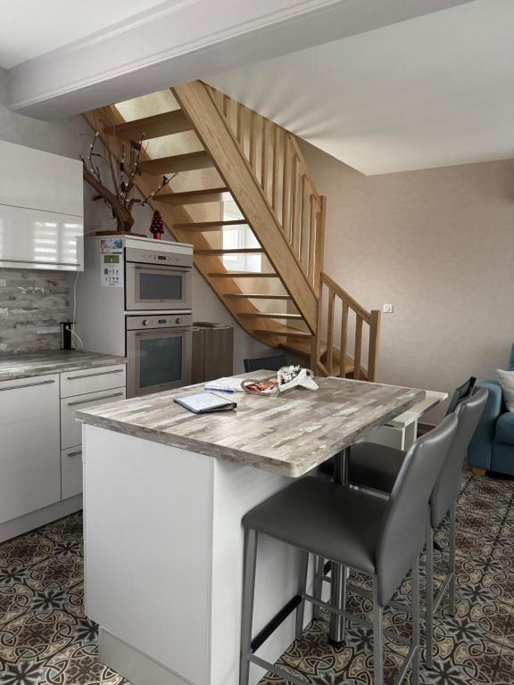 eine Küche mit einer Theke mit Stühlen und einer Treppe in der Unterkunft Gîte avec piscine in Lestrem