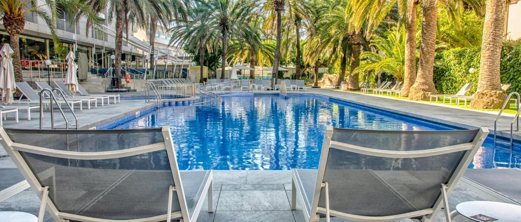 a swimming pool with chairs and palm trees at Bordoy Cosmopolitan in Playa de Palma