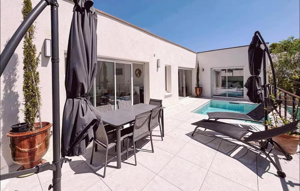 eine Terrasse mit Tisch und Stühlen und einem Sonnenschirm in der Unterkunft Maison Piscine Nîmes in Saint-Césaire