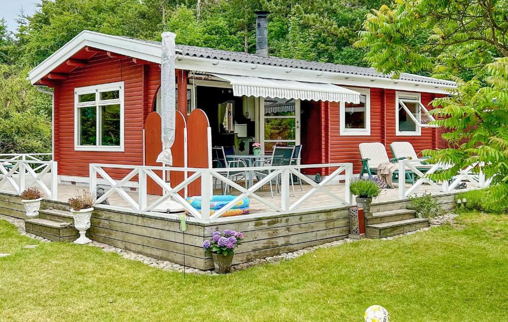 una cabaña roja con un porche y una tabla de surf en Lovely Home In Asnæs With Wifi, en Høve Strand