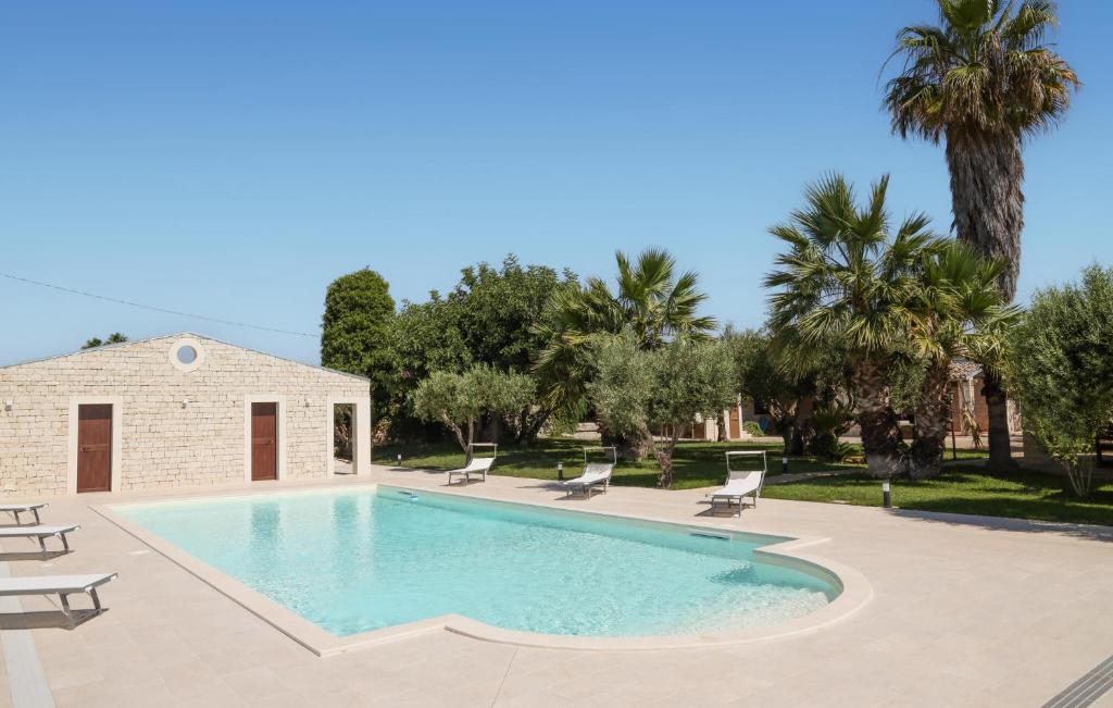 a swimming pool in a yard with chairs and trees at Lovely Home In Modica in Modica