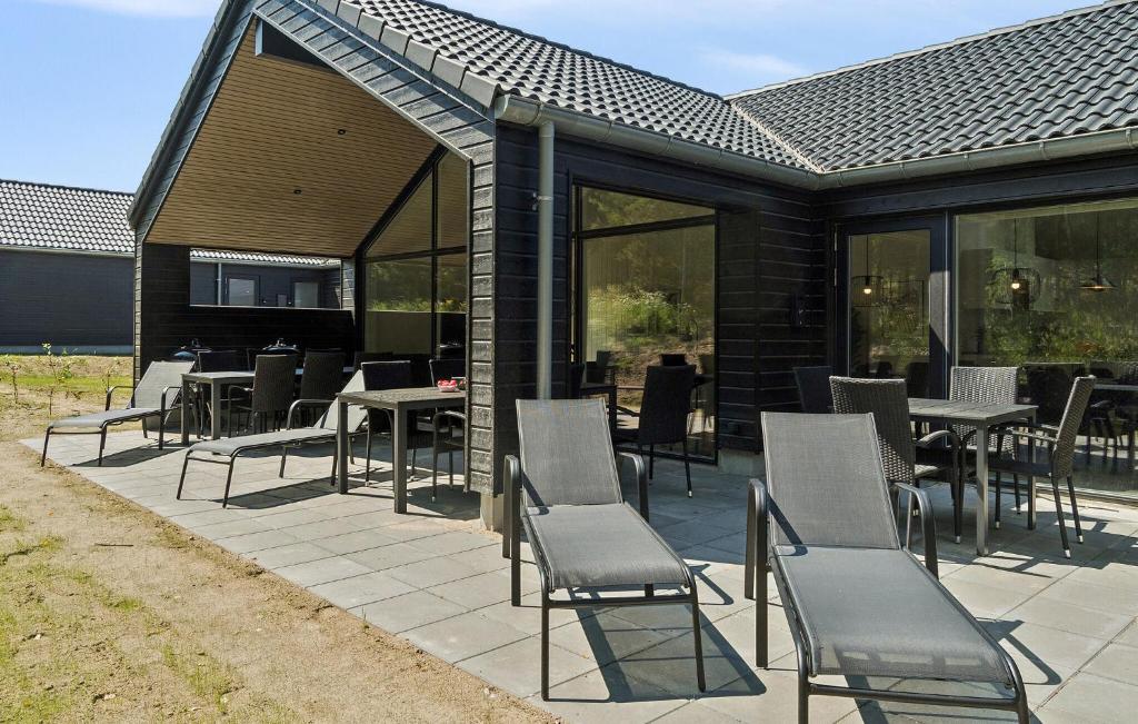a patio with chairs and tables and windows at Cozy Home In Glesborg With Sauna in Fjellerup