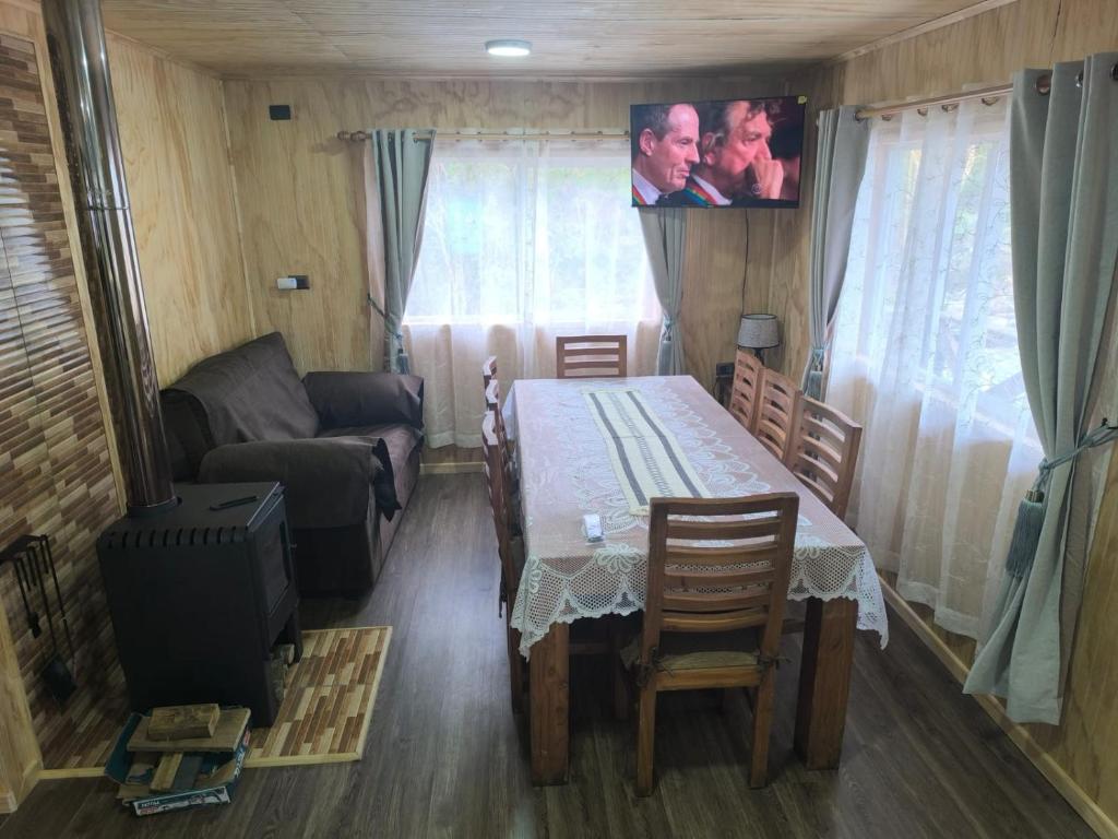 a living room with a table and a couch and a tv at Cabaña La Casona in Chaitén