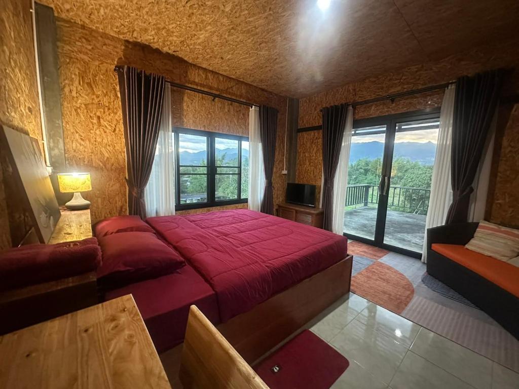 a bedroom with a red bed and a large window at Pharit guesthouse in Pai