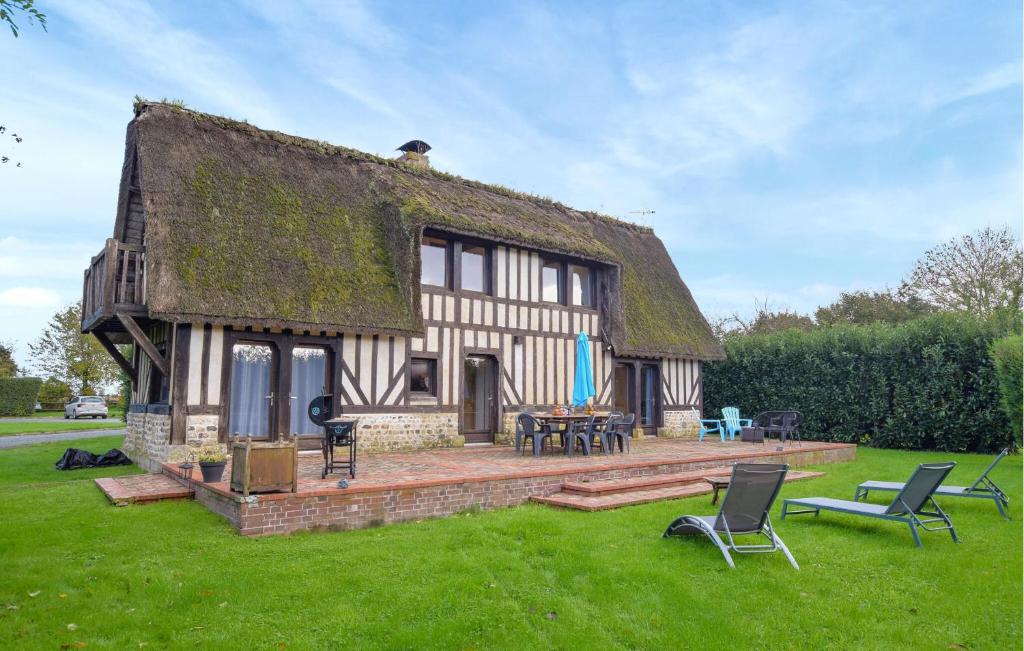 ein Haus mit einem Strohdach mit Stühlen und Tischen in der Unterkunft Confortable Maison Normande in Saint-Léger-sur-Bonneville