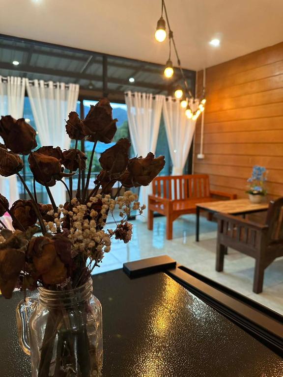 a vase with flowers on a table in a living room at Pharit guesthouse in Pai