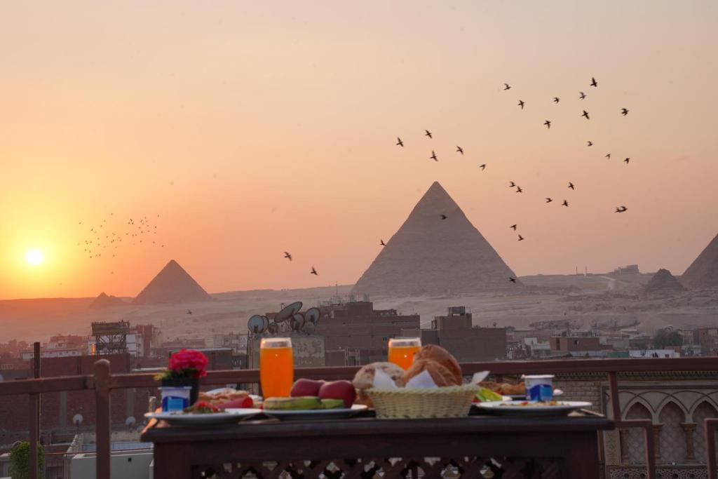 einen Tisch mit Essen auf einem Balkon mit Pyramiden in der Unterkunft Pyramids Khan Hotel in Kairo