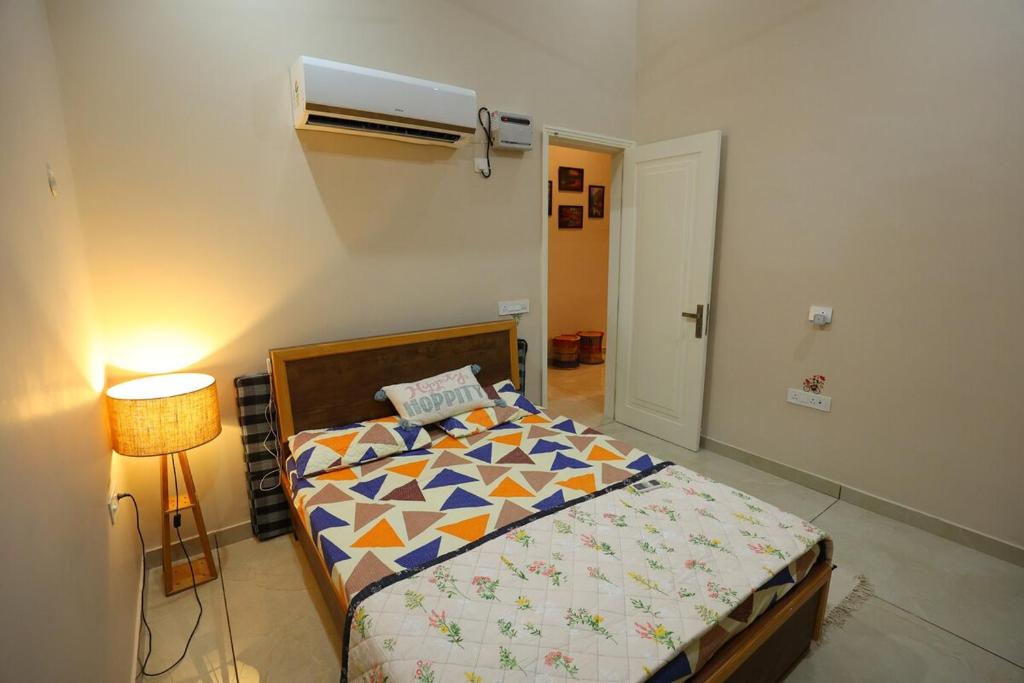 a bedroom with a bed and a lamp next to a bed sidx sidx at Sariska Bliss Farm, #2-BHK, #Private Pool & Garden in Alwar