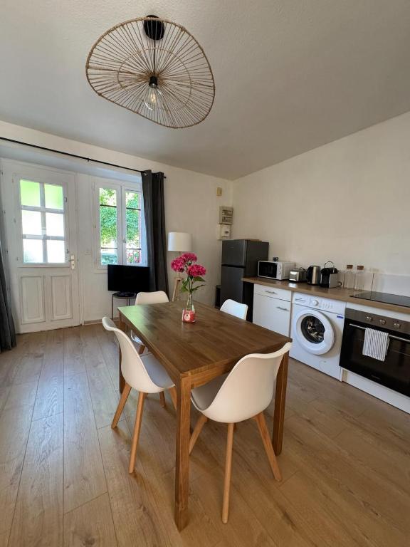 a kitchen with a wooden table and white chairs at La Petite Maison mitoyenne in Condeissiat