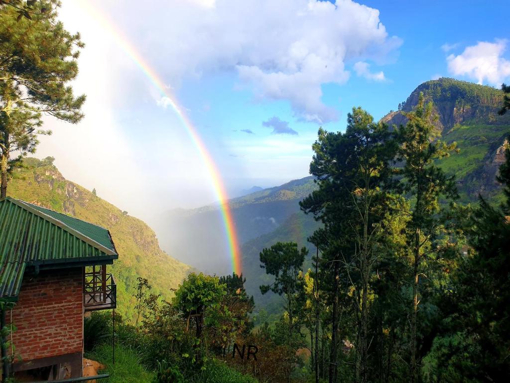 埃拉艾拉山舒适小屋的山间彩虹，远处有建筑物和树木。
