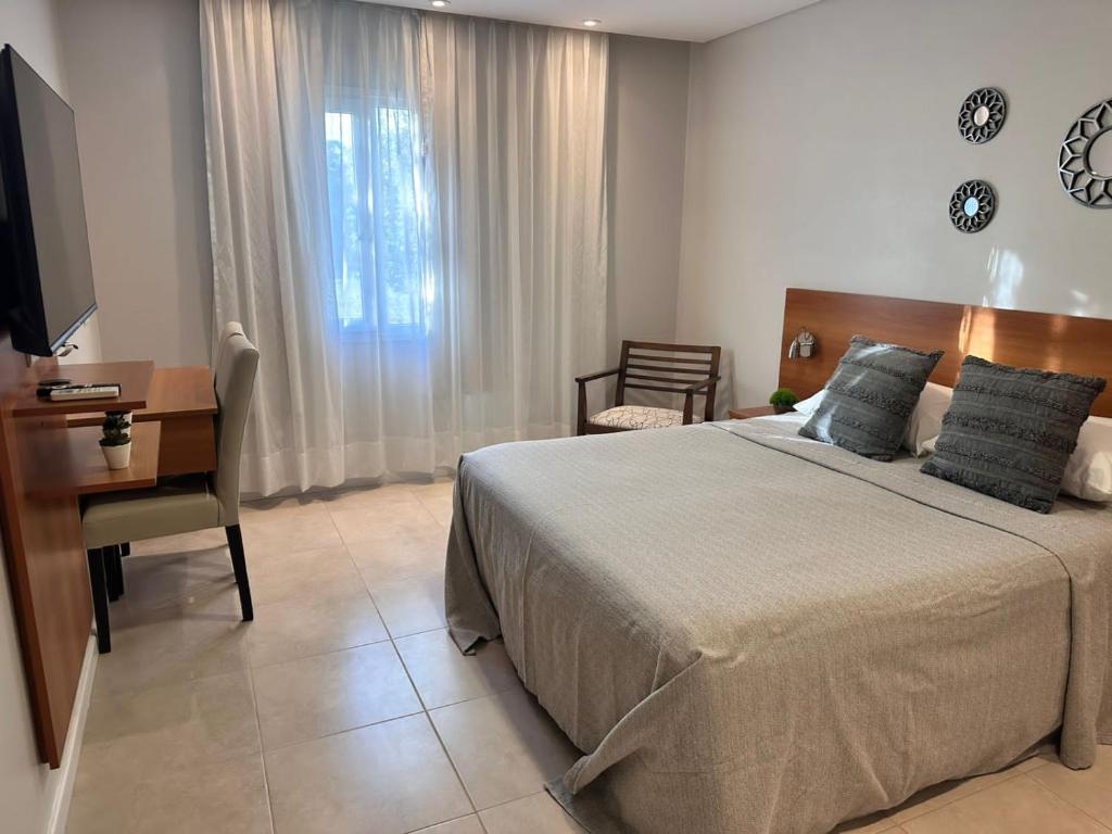 a bedroom with a bed and a desk and a television at Suite del Sol 106 in Pinamar