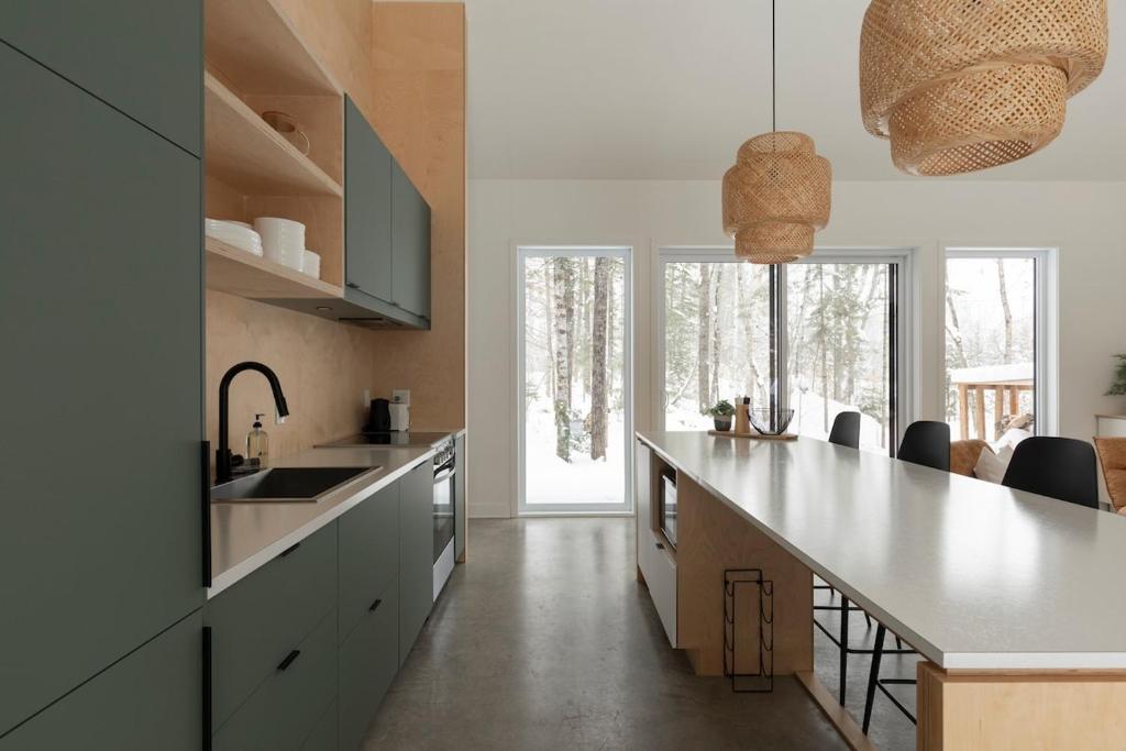 a kitchen with white counters and a large counter top at Woodland - Terrace - Fire pit - 15min Tremblant in La Conception