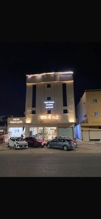 two cars parked in front of a building at night at آنتري للشقق المخدومة in Buraydah