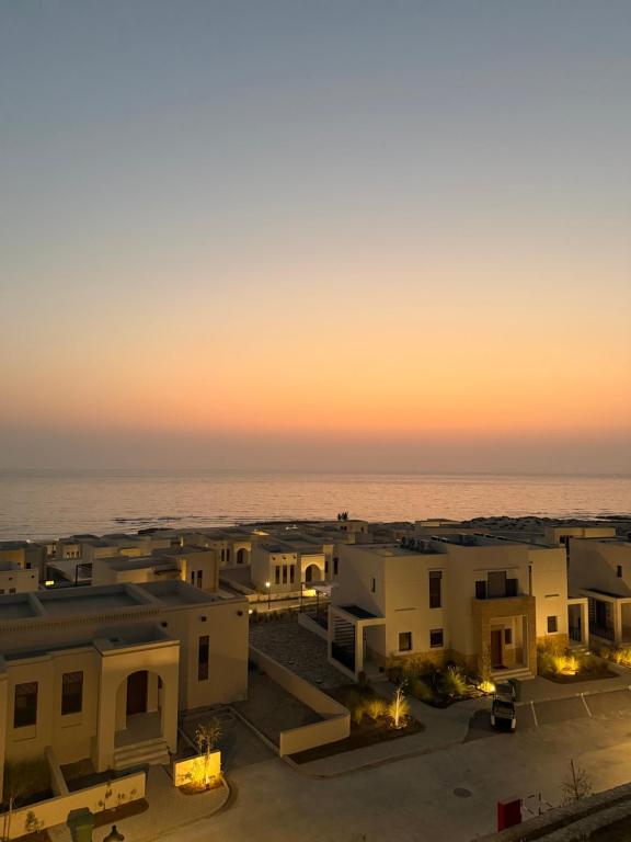 a view of the ocean from a building at sunset at Sifahbeachfront Apartment in As Sīfah