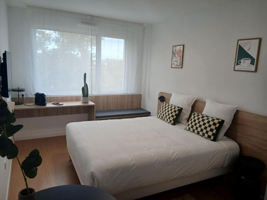 a bedroom with a bed with pillows and a window at Sweetly Mérignac Aeroparc in Mérignac