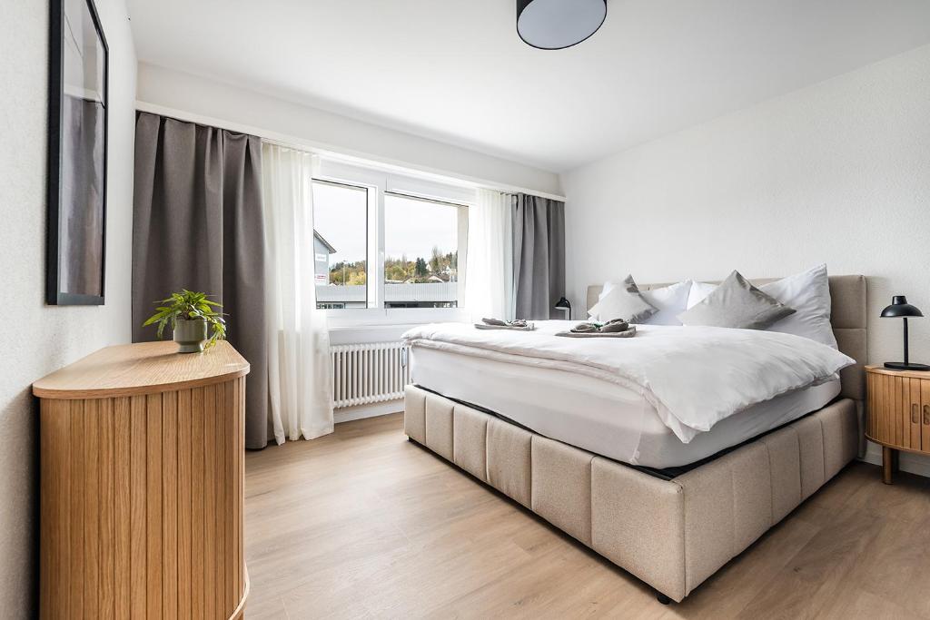 a white bedroom with a large bed and a window at GOLD-APARTMENT 2 !Gratis Parken, Free Parking! in Frauenfeld