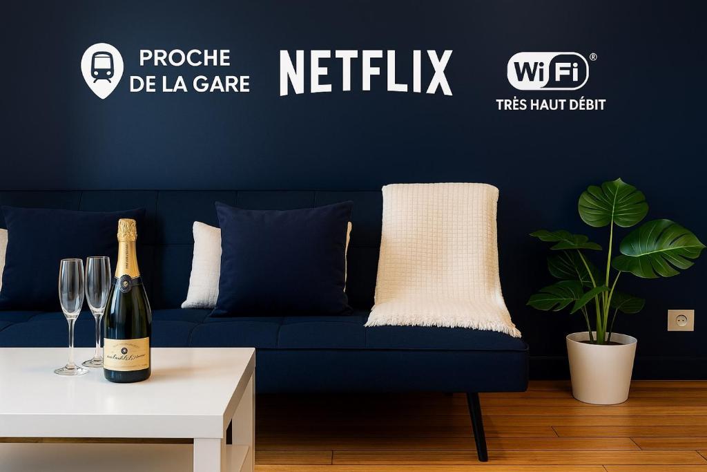 Un sofá azul en una sala de estar con una botella de vino. en Élégance & confort - aux portes de Paris, en Aulnay-sous-Bois