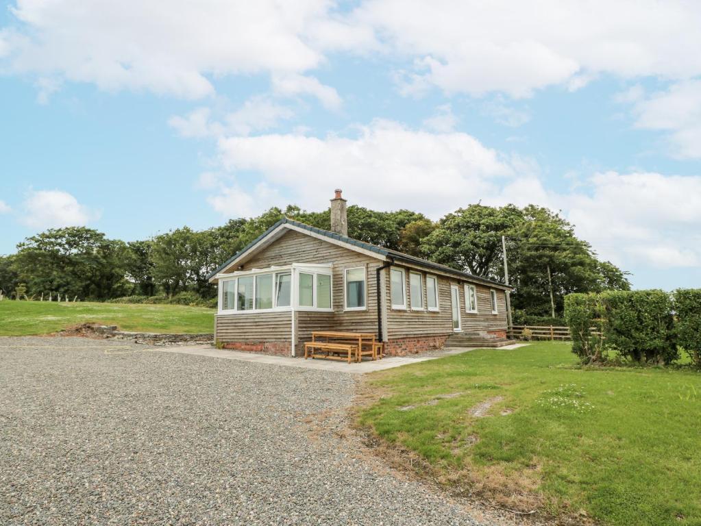 une petite maison en bois avec une allée en gravier dans l'établissement The Dairy, à Glasserton