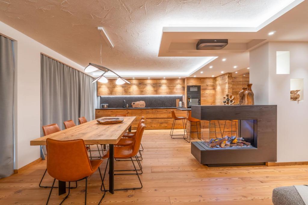 ein Esszimmer mit Tisch und Kamin in der Unterkunft BRENTA ALTA ALPINE LODGE MhD in Madonna di Campiglio