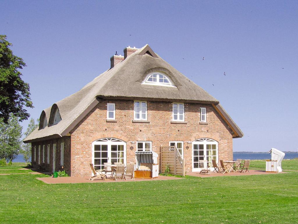 a large brick house with a thatched roof at Ferienhaus "Lachmöwe" in Vaschvitz