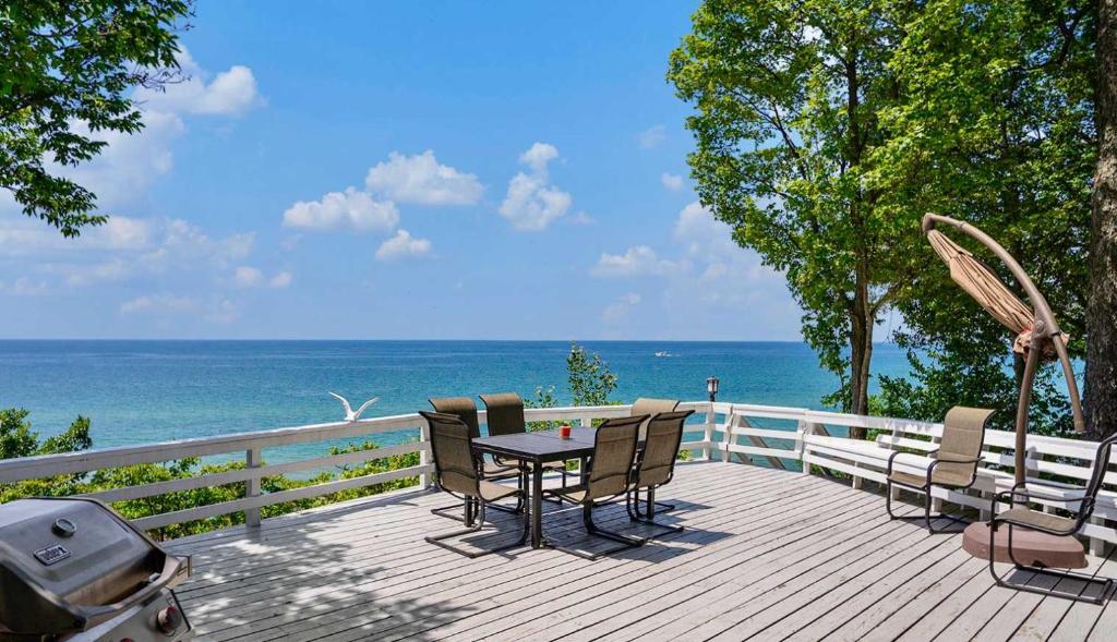 een dek met een tafel en stoelen en de oceaan bij Private Beachfront Lake Michigan Getaway in West Olive