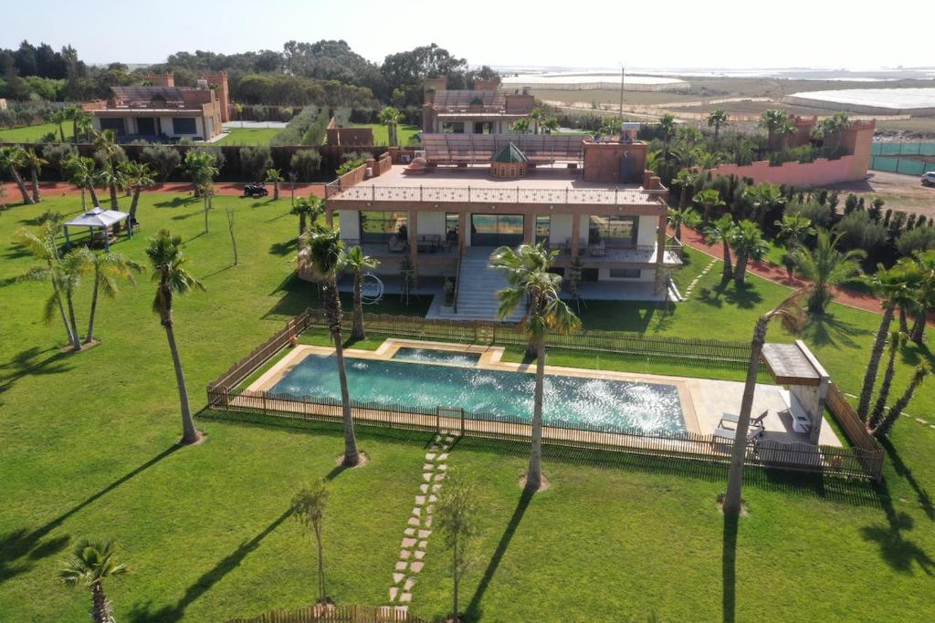 ein Luftblick auf ein Haus mit einem Pool und Palmen in der Unterkunft Villa Royal Paradise - Pool, Football, Tennis, Cinema in Sidi Bibi