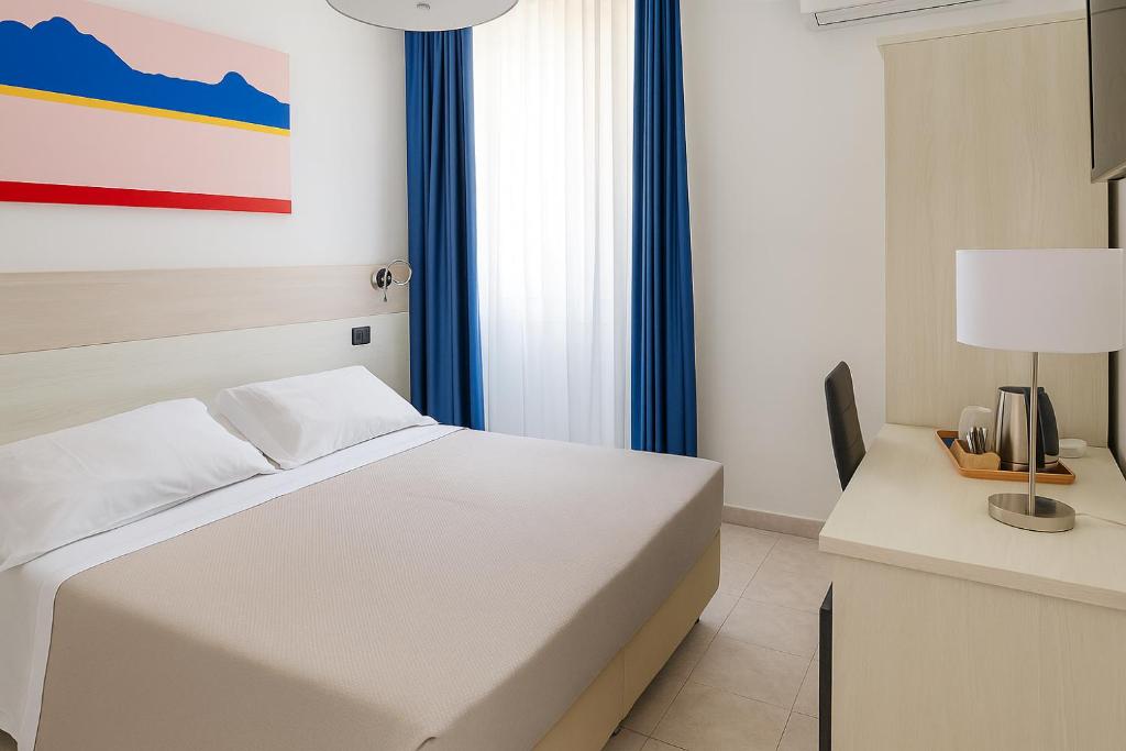 a bedroom with a white bed and a desk with a lamp at Hotiday La Spezia Centrale in La Spezia