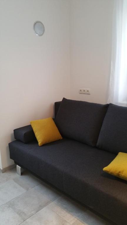 Un sofá negro con dos almohadas amarillas. en Opatment - die Nussschale, en Mörbisch am See