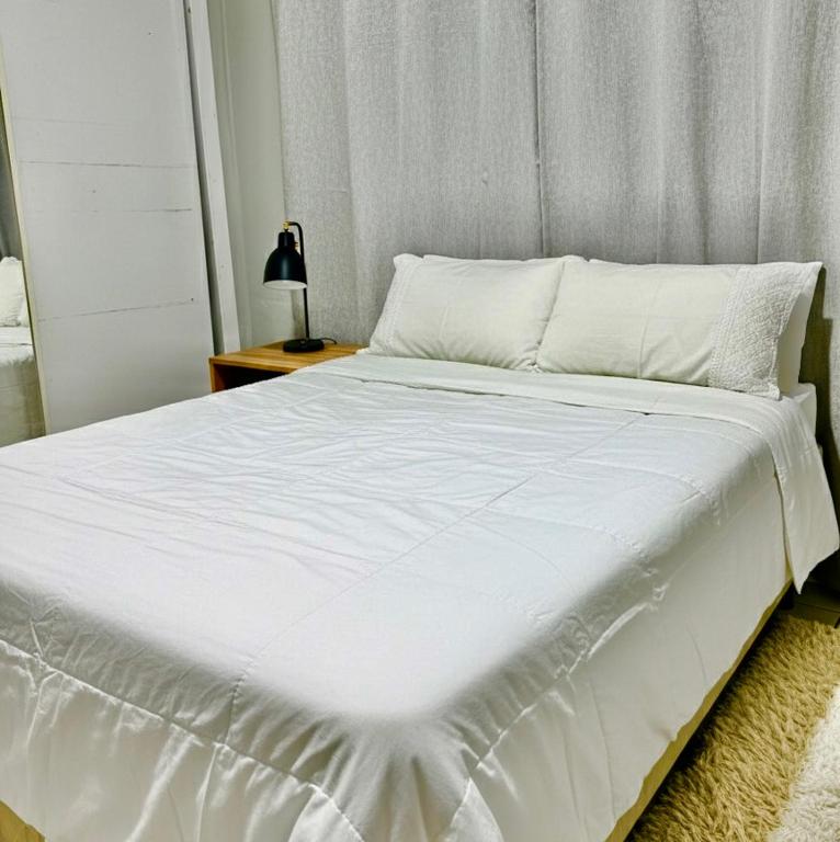 a large white bed in a room with a table at Fique no coração de Belém in Belém
