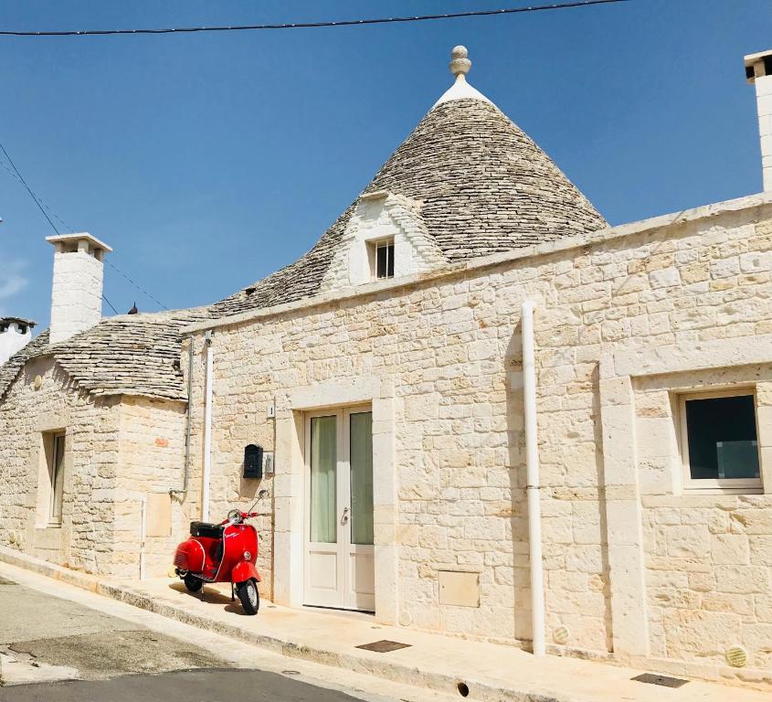 Un patinete rojo aparcado frente a un edificio de piedra en Trullo Stella Luxury Trullo, en Alberobello