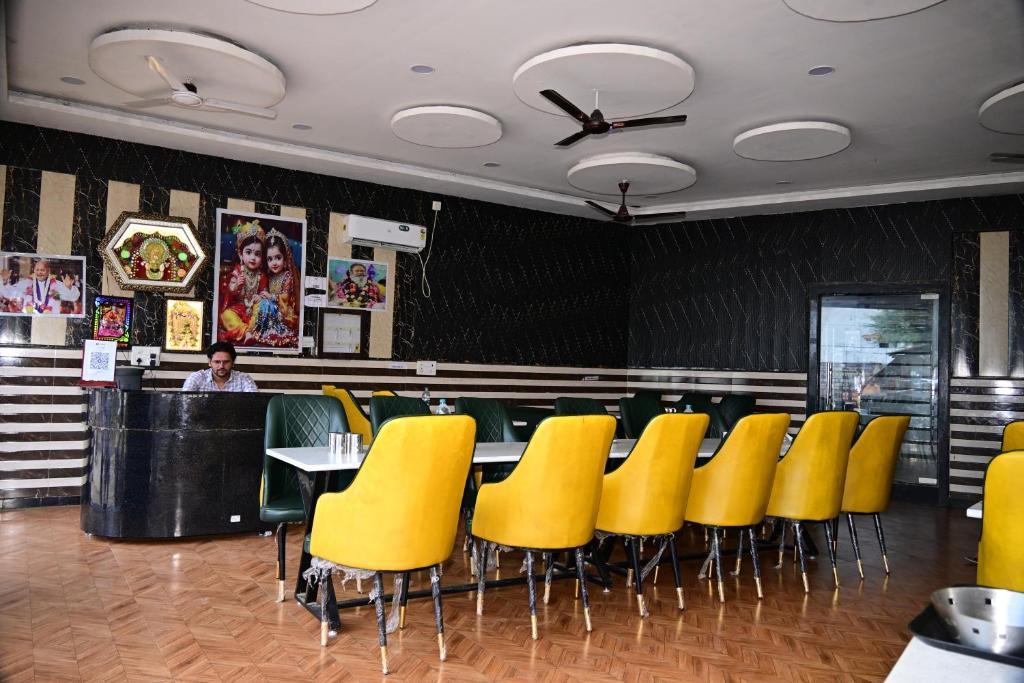 une salle à manger avec des chaises jaunes et un bar dans l'établissement Namami Atithi Grah, à Barsāna