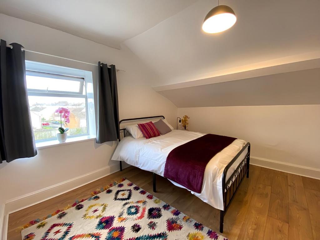 a bedroom with a bed and a window and a rug at 4-Bedrooms - Perfect for those working in Bridgend in Bridgend