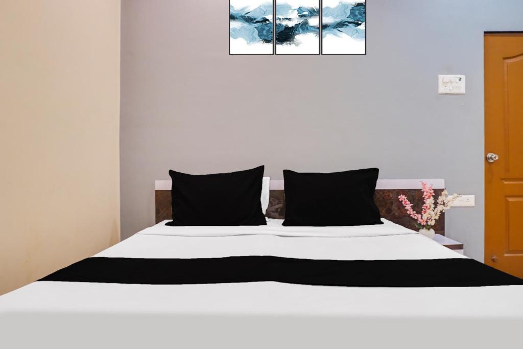 a bedroom with a white bed with black pillows at Hotel O Atithi Lodge in Wagholi