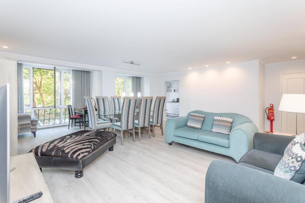 a living room with a blue couch and chairs at BeGuest Jardim Quinta da Alagoa Luxury Stay in Carcavelos