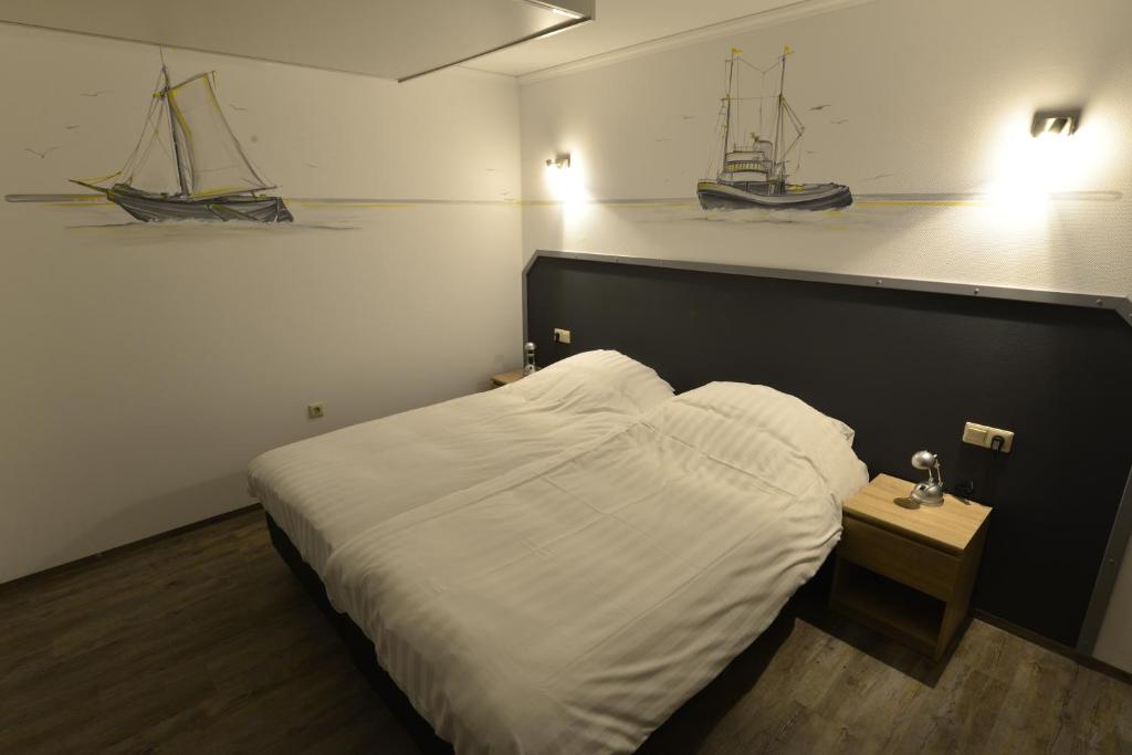 sypialnia z łóżkiem i dwie łodzie na ścianie w obiekcie Havenzicht Westkant w mieście Dinteloord