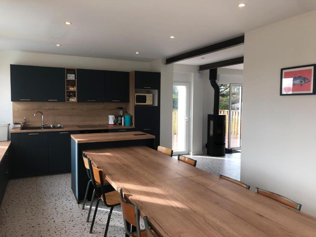 una cucina con un lungo tavolo in legno e un bancone di Menbleis, maison familiale a Plounéour-Trez