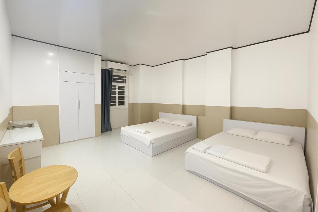 Un dormitorio con dos camas y un escritorio y una mesa. en CKC Motel - Near Can Tho City Center, en Can Tho
