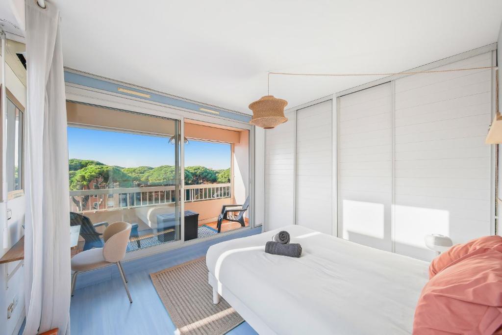 ein Schlafzimmer mit einem weißen Bett und einem Balkon in der Unterkunft Piscine & Soleil à Hyères - T3 spacieux avec Clim & Extérieurs in Hyères