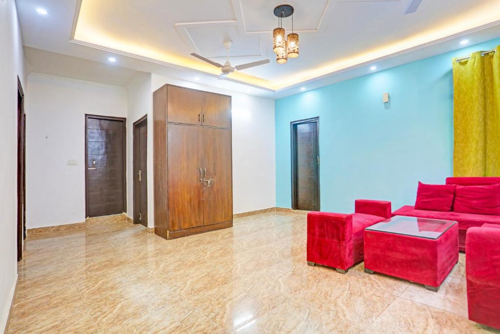 a living room with red chairs and a wooden cabinet at Hotel O Yash stay in New Delhi